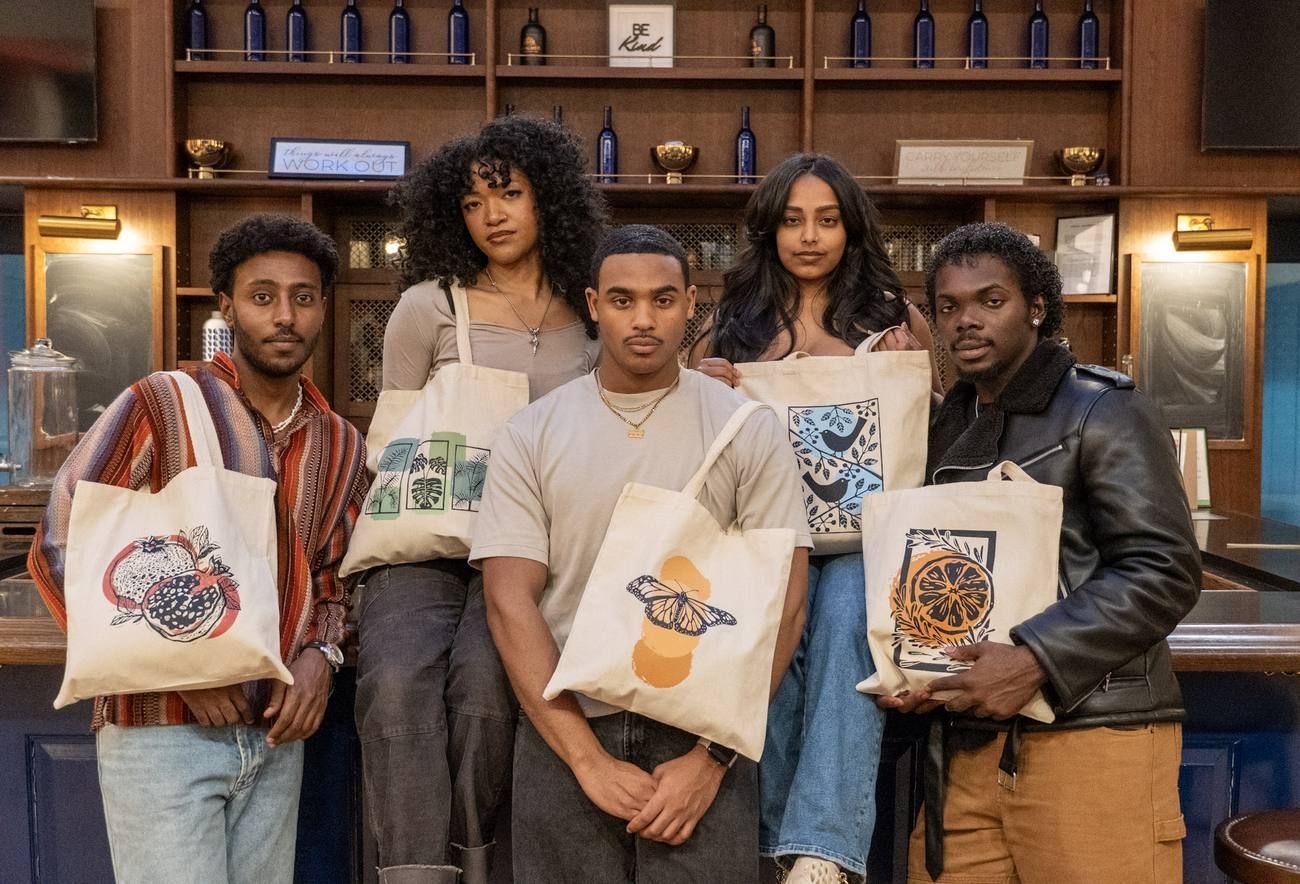 Five people holding Angaza Taa totes with pomegranate, leaf, butterfly, bird and citrus prints