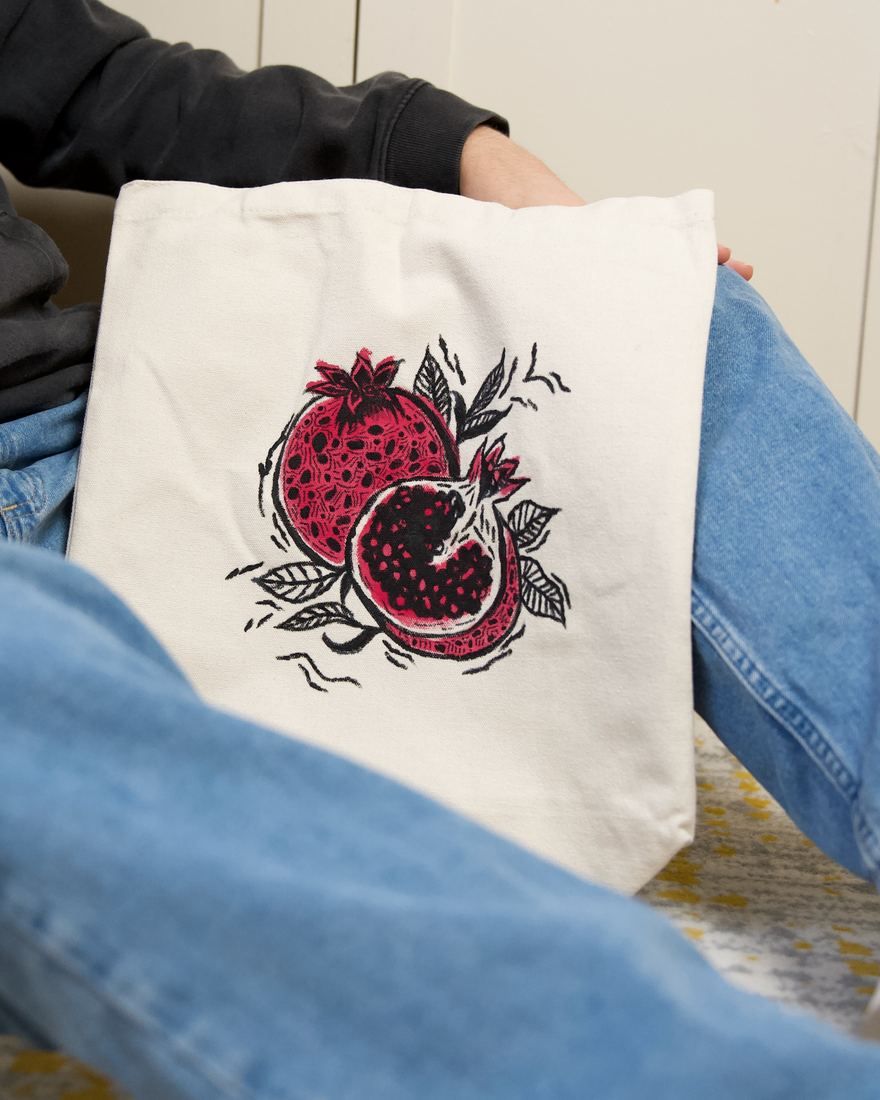 Pomegranate tote: a split pomegranate over a warm wash of color
